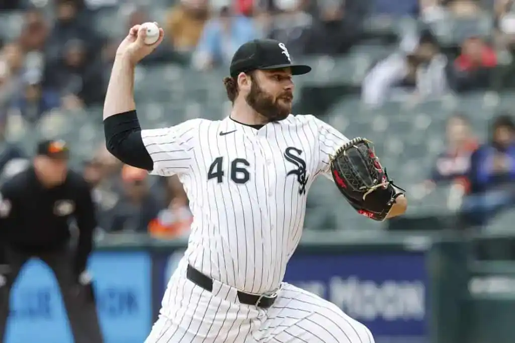 A baseball player in a white and black pinstriped uniform prepares to pitch on