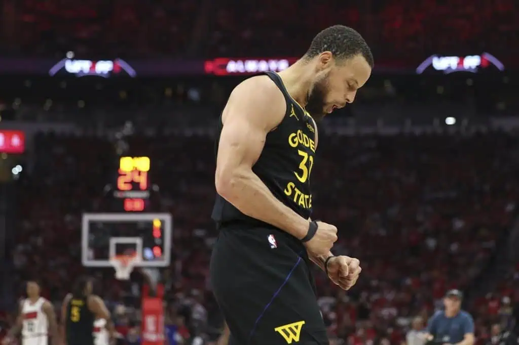 6 A basketball player in a Golden State Warriors jersey celebrates a successful play during an intense game, fans cheering in the background.