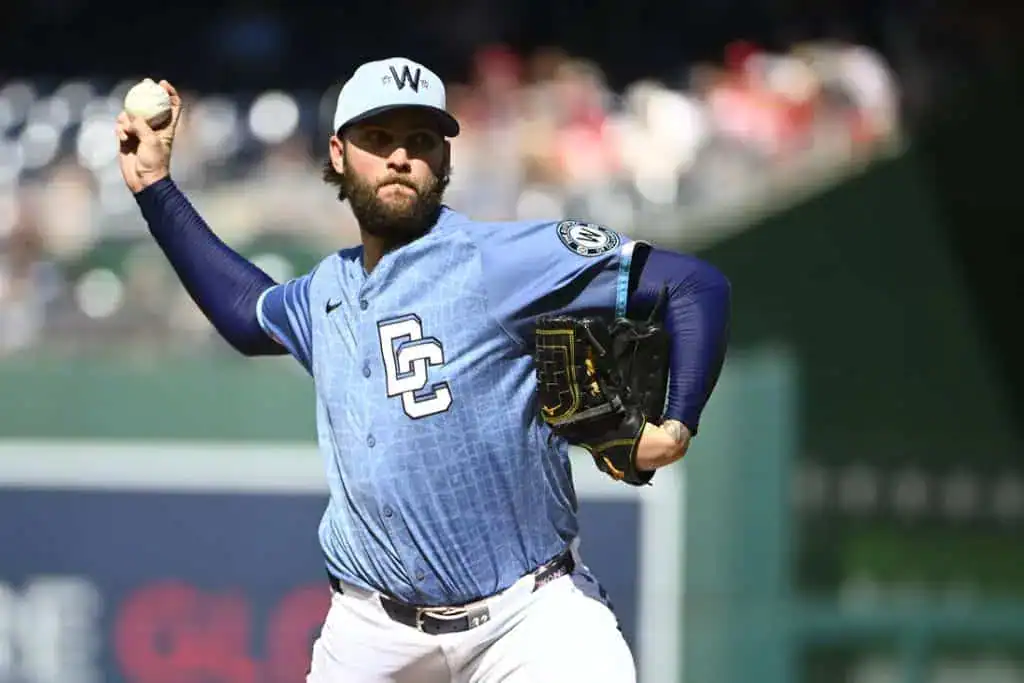 A pitcher in a blue sports jersey prepares to throw a baseball