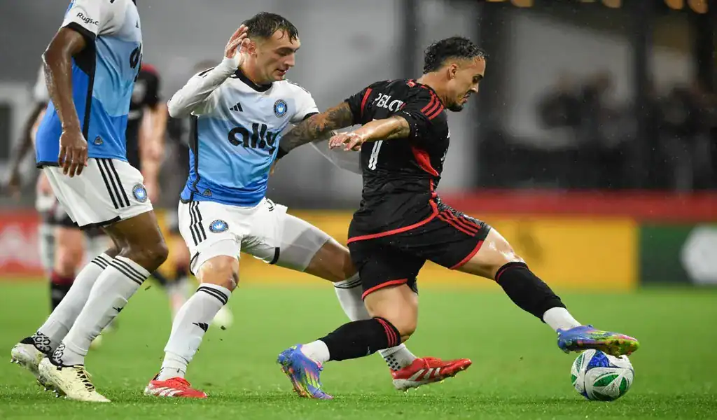 DC United player challenges New England Revolution defender for possession