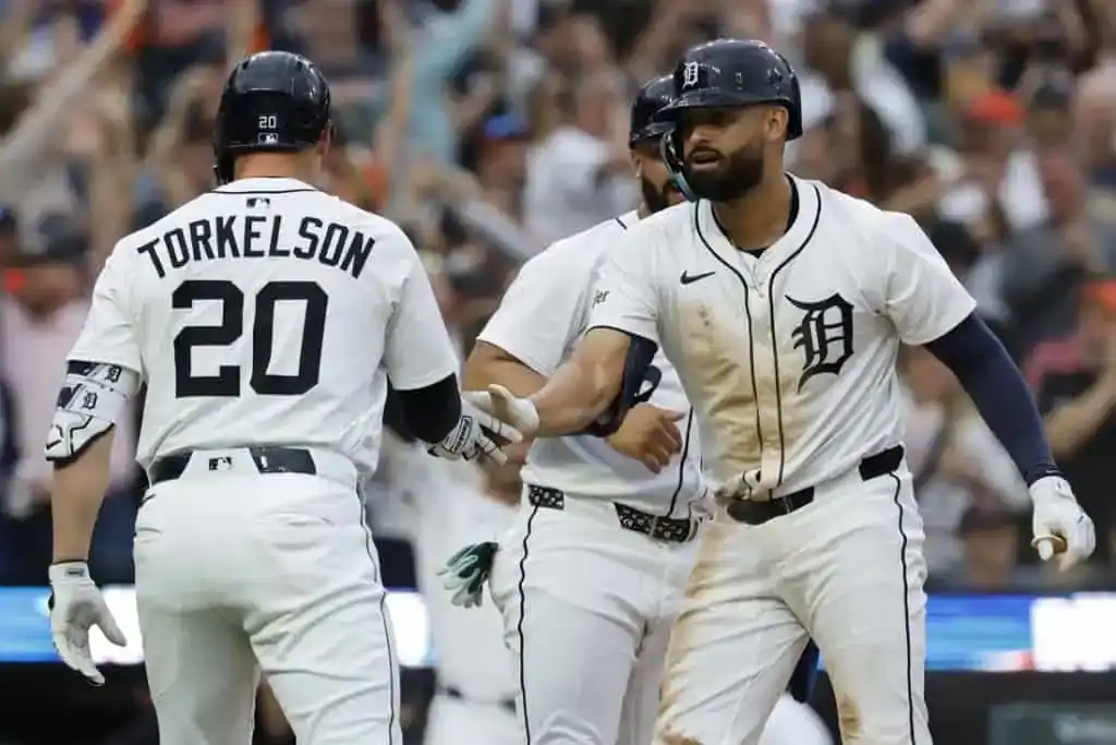 Detroit Tigers players celebrate a home run, with Torkelson in a white jersey and black cap, highlighting team unity and excitement.