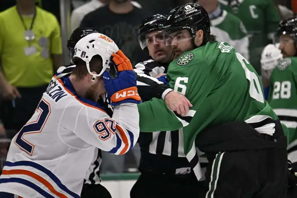 An intense moment in hockey as players grapple, with officials intervening to separate them during a heated game.
