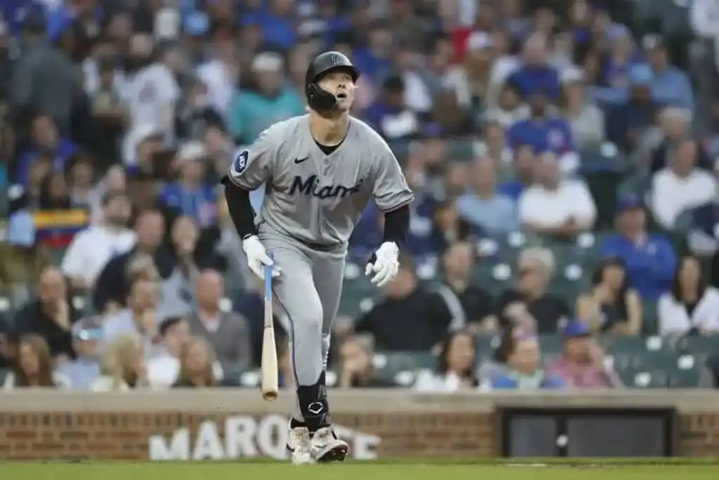 4 A player in a gray Miami Marlins uniform runs towards first base, bat in hand, with a blurred crowd in the background.