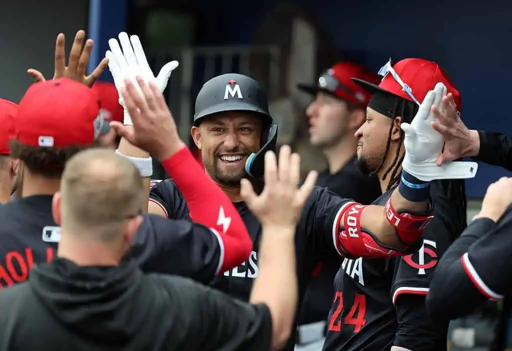 A group of baseball players in team jerseys celebrate with high-fives, showcasing excitement and camaraderie in the dugout.