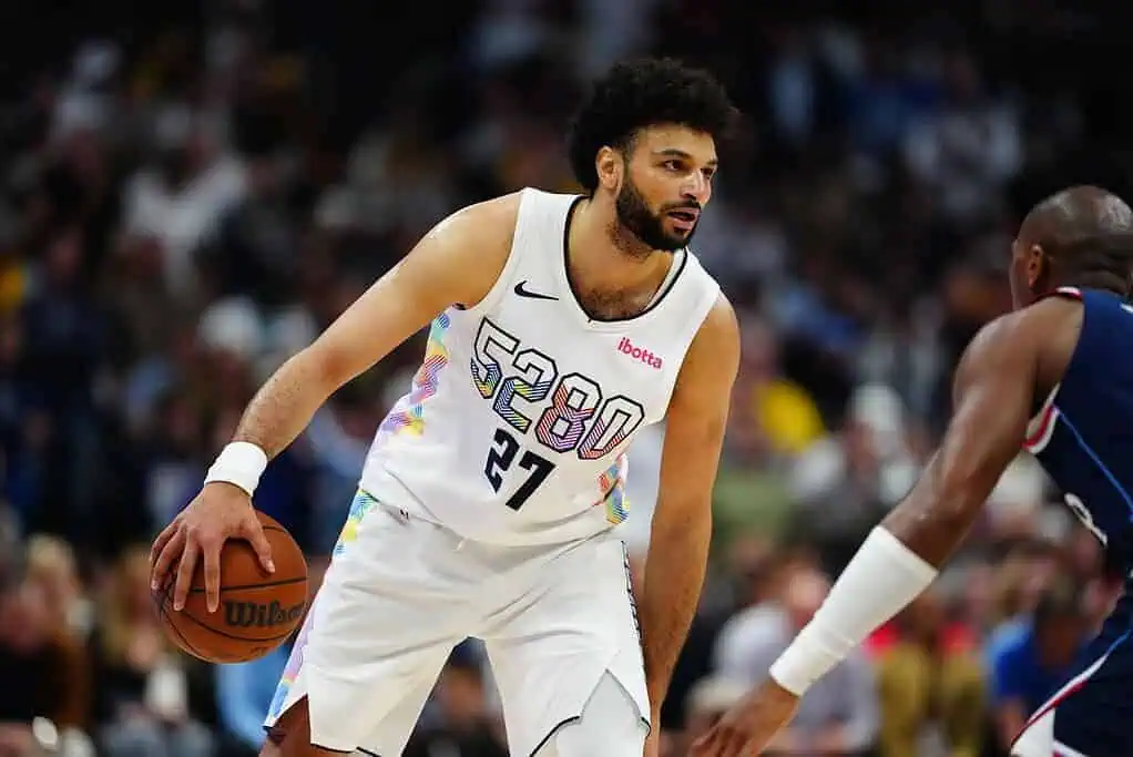 5 A basketball player dribbles a ball on the court, wearing a colorful jersey with the number 27, during an intense game.
