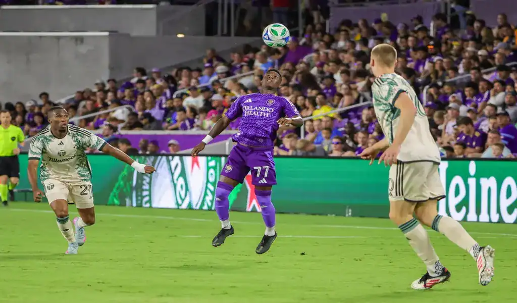 Orlando City player heads the ball against Atlanta United defenders