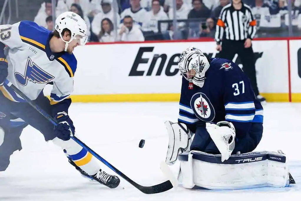 A St. Louis Blues player attempts to score against a Winnipeg Jets goalie during an intense hockey match