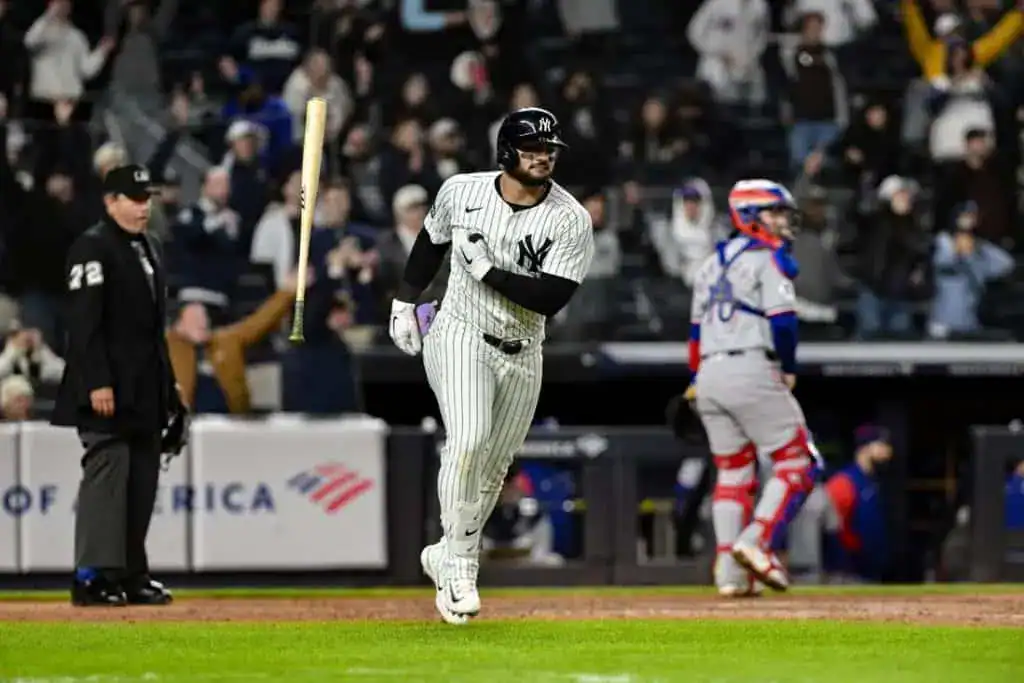 3 A New York Yankees player runs enthusiastically after hitting the ball, with fans cheering in the stands behind him.