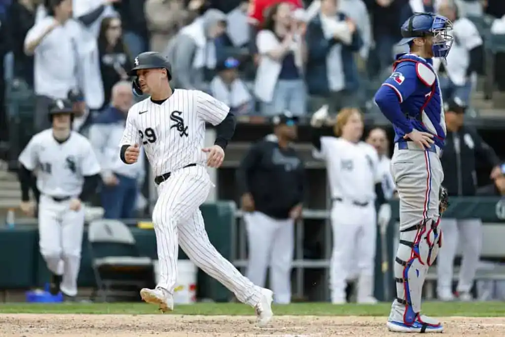 1 A Chicago White Sox player rounds the bases, celebrating a run, while a Texas Rangers catcher watches in disappointment, surrounded by cheering fans.