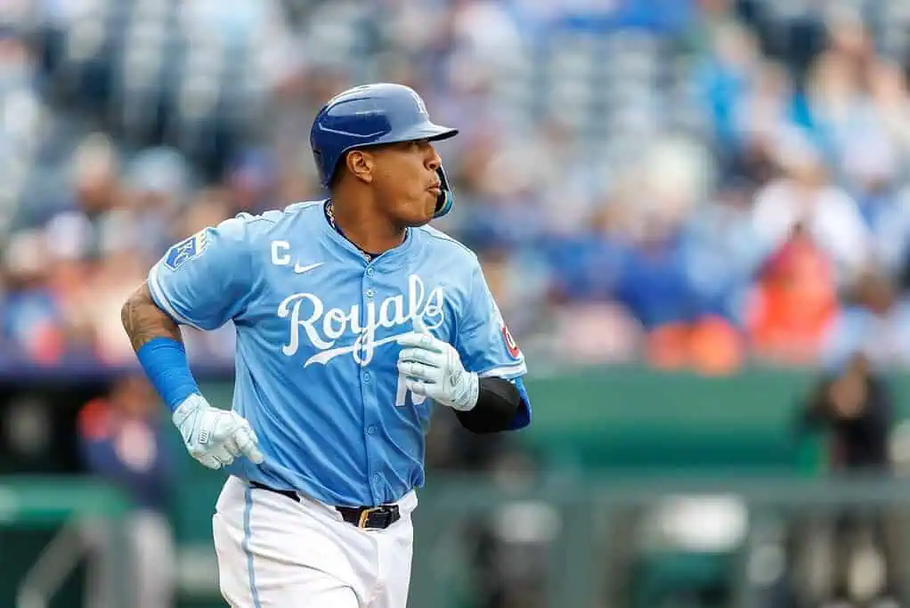 A baseball player in a light blue Royals jersey runs towards the dugout during a game
