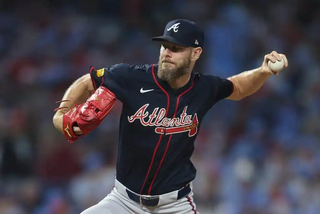7 A pitcher in a dark blue Atlanta Braves jersey winds up to throw a baseball, showcasing focused determination on the mound.