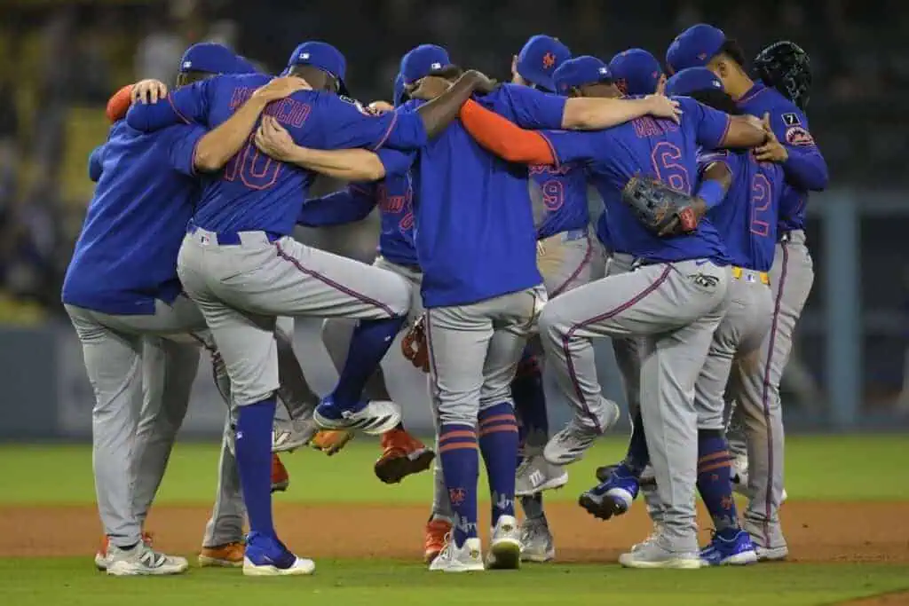 2 A group of baseball players in blue jerseys huddle closely, celebrating in a lively, interconnected pose on the field.
