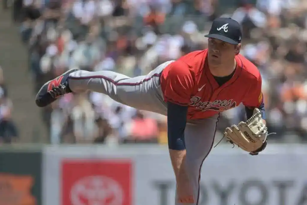 9 A pitcher in a red Braves uniform prepares to throw a baseball, showcasing intense focus amid a crowded stadium backdrop.