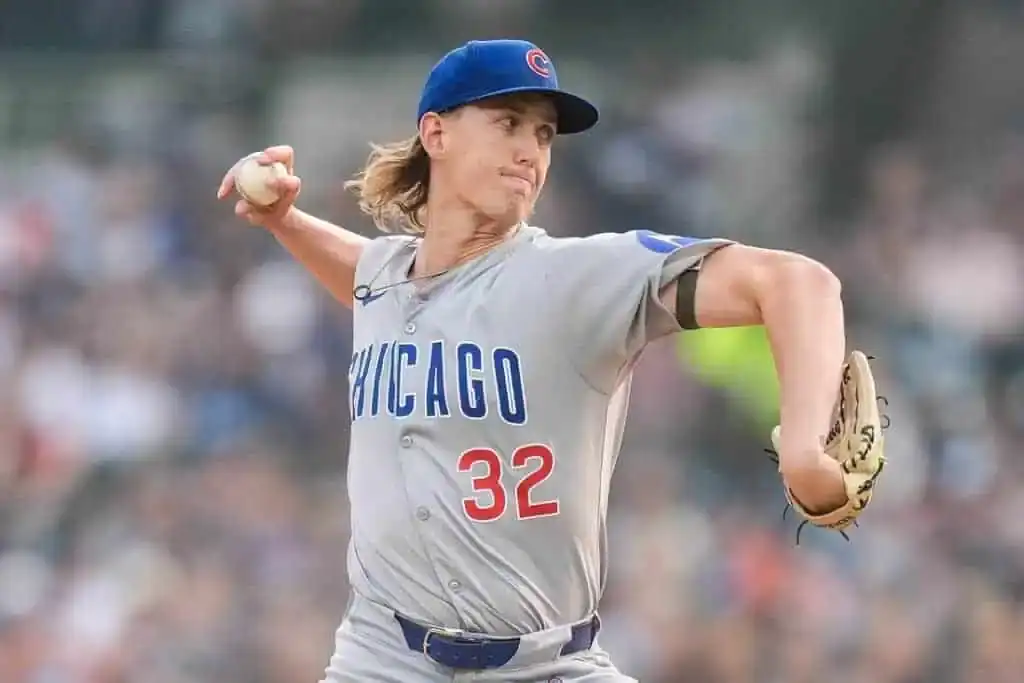 A Chicago Cubs pitcher in a gray uniform winds up to throw a baseball during a game, showcasing a dynamic action shot.
