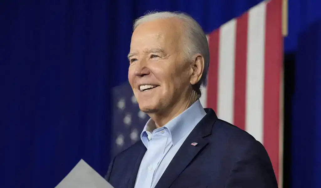 Imagen de Joe Biden sonriendo con una bandera de Estados Unidos al fondo, utilizada para apuestas, probabilidades y predicciones políticas.