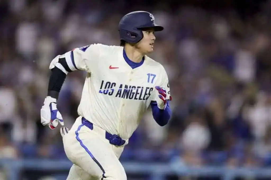 A baseball player wearing a white jersey with "LOS ANGELES" printed, sprinting on the field during a night game.