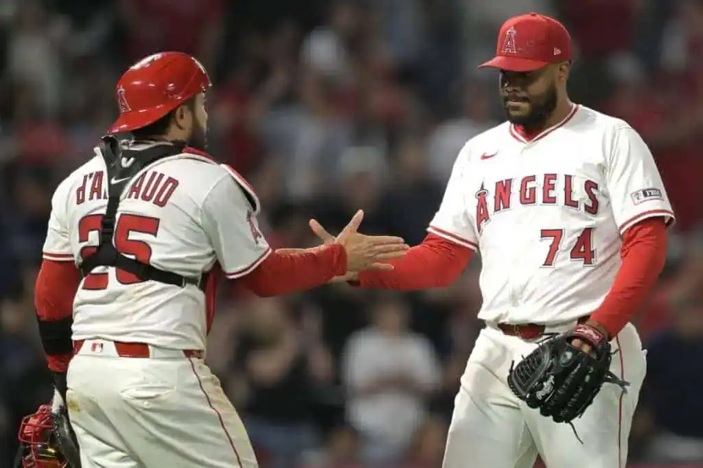 Two Los Angeles Angels baseball players celebrate a successful play with a handshake on the field, showcasing team camaraderie.
