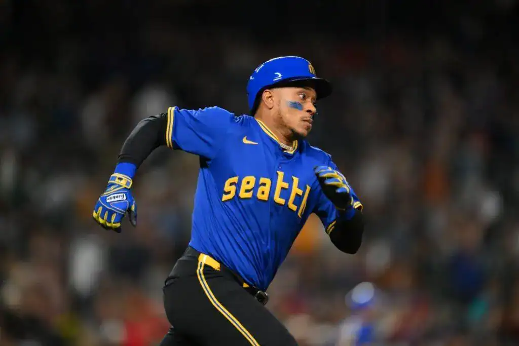A player in a blue Seattle Mariners jersey sprints confidently across the field during an intense baseball game.