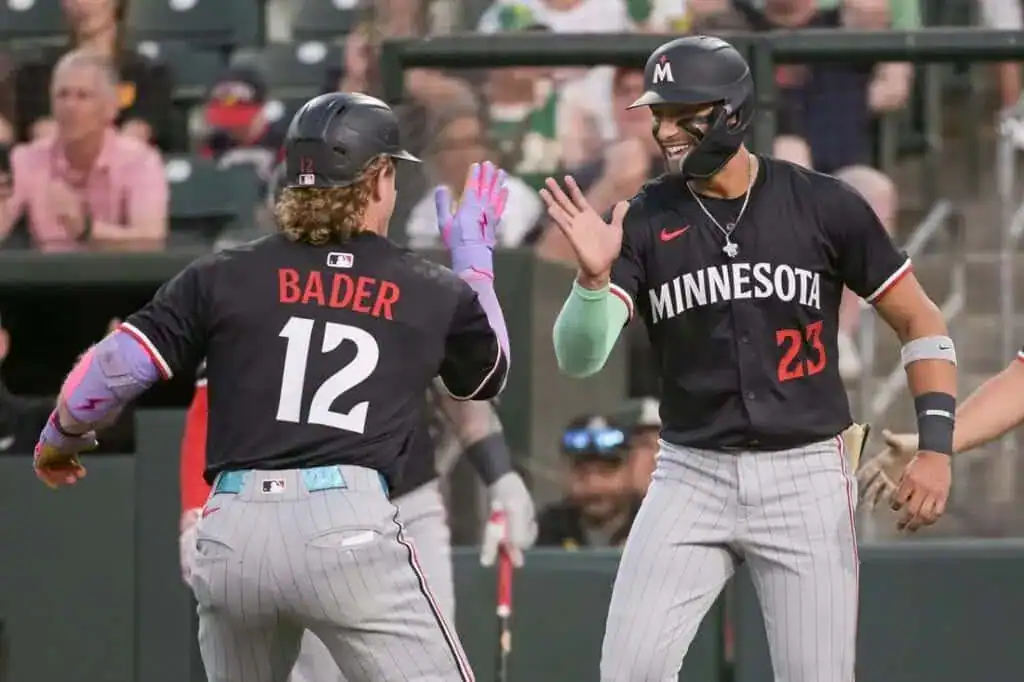 9 Two baseball players in black jerseys celebrate in a stadium, one with "BADER" on the back, while the crowd cheers in the background.