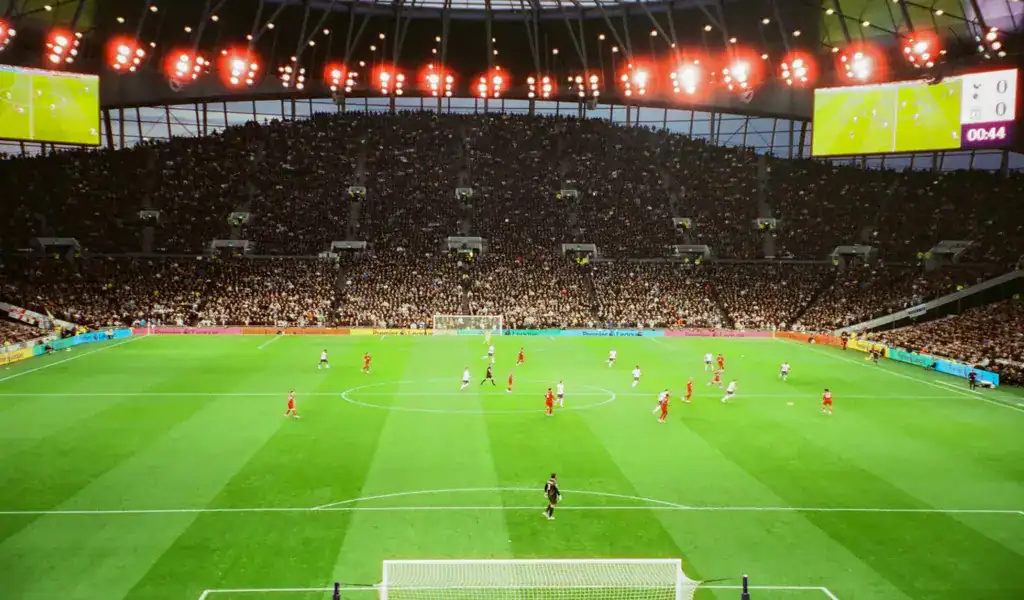Premier League soccer match in a packed stadium, illustrating factors like wages, xG, and age curves guiding bookmakers