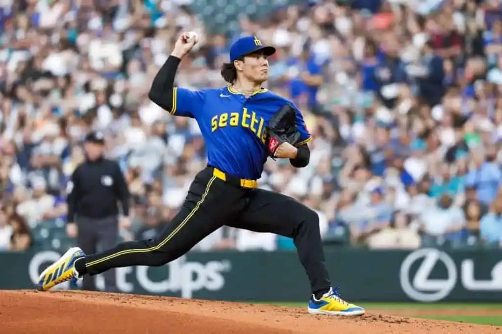 8 A baseball pitcher in a blue Seattle Mariners jersey winds up on the mound during a game, with fans in the background.