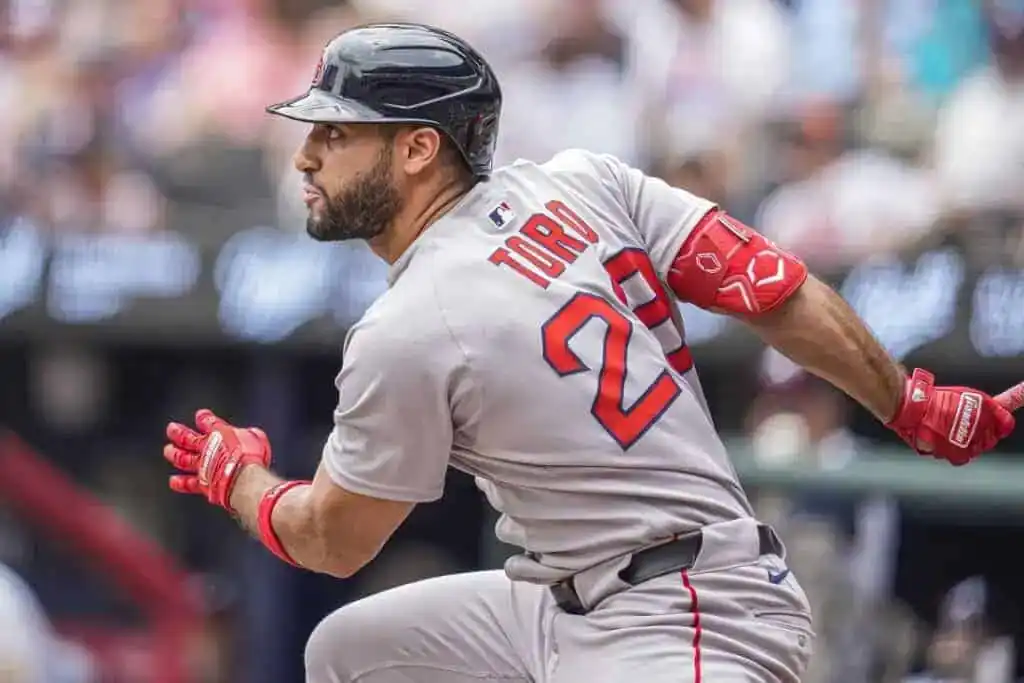 8 A baseball player in a gray uniform swings a bat, showing intense focus during a game. Spectators are blurred in the background.
