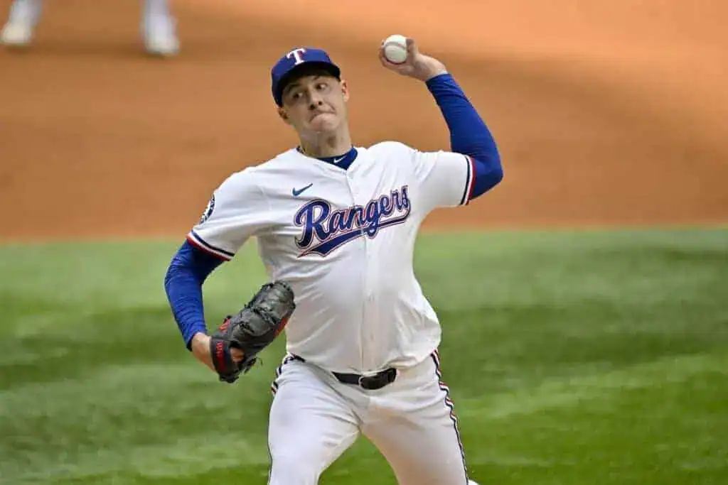A Texas Rangers pitcher prepares to throw a baseball, showcasing focused stance and uniform against a baseball field backdrop.